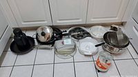 Overview photo showing pans, pots, Pyrex dishes, and other items on kitchen floor