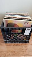 Milk crate filled with 55 various LP records showing edges of album covers and sleeves.