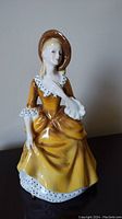 Front view of Royal Doulton Sandra B figurine showing detailed facial features and yellow dress with white and black polka dot trim.