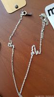 Thin sterling silver chain with broken section, showing clasp and chain links.
