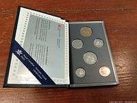 Open blue casing displaying six Canadian coins arranged in foam slots along with a certificate on the left side.
