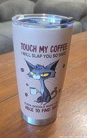 Front side of travel mug with grumpy cat cartoon and warning text about coffee.
