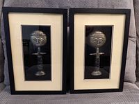 Two wood framed prints under glass featuring stylized figures in grayscale, with white mats and black inner borders.