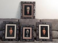 Four wood-framed African tribal mask art pieces arranged on a couch, showing different frame styles and masks.