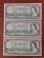 Three Canadian 1954 one dollar bills laid out showing front side with portrait of Queen Elizabeth II and serial numbers visible.