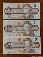 Front view of three consecutive 1986 Canadian $2 bills featuring Queen Elizabeth II portrait.