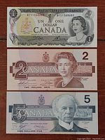 Photo showing three Canadian bills: 1973 one dollar, 1986 two dollars, and 1986 five dollars, displayed vertically.