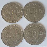 Reverse side of four 1935 Canadian five cent coins showing denomination, maple leaves, and year.