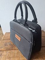 Front angle of black thermal lunch bag showing padded dual handles and front pocket with Lidengors label.