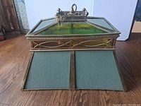 Image of vintage games room light lying on wood floor showing top and side with brass frame, green glass, and hanging chains visible