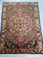 Full view of rug front showing geometric medallion design with muted pink, navy, green, ivory and yellow accents