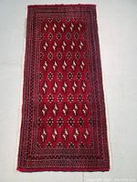 Full view of the rectangualr red Turkman style Persian rug with geometric motifs and multiple borders.