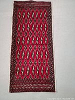 Full length photo of the red Turkman rug showing geometric patterns and border details.
