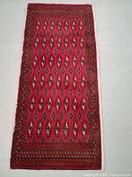 Full view of the rectangular hand knotted wool Turkman rug with geometric motifs and red as the primary color.