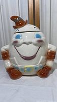 Front view of the 1960s vintage McCoy Brush Pottery Humpty Dumpty cookie jar showing the character's smiling face, brown hat, gloves, belt, and shoes.