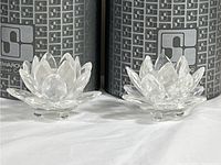 Pair of clear Swarovski crystal mini rose figurines displayed side by side in front of their original branded boxes.