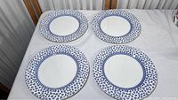Four matching English ironstone plates arranged on a surface showing the entire set.