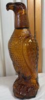 Side view of the amber glass eagle decanter showing detailed texture and curved beak stopper.