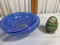 Front angled view showing both pieces, large blue and white swirled bowl and smaller greenish multi-colored egg-shaped piece.