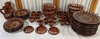 Overview of entire pottery dinnerware set including plates, bowls, small cups, and pitchers arranged on a table.