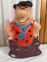 Front view of the Fred Flintstone piggy bank showing detailed face, outfit colors, and overall shape.