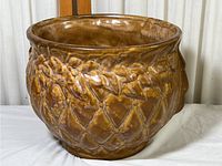 Front angle view of the brown glazed McCoy pottery planter showing textured diamond and leaf design.
