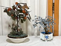Two vintage miniature trees side by side on a table, showcasing size and condition.