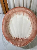 Top view of large seashell-shaped pottery with pink and white glaze.