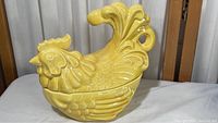Side view of yellow ceramic rooster cookie jar showing detailed features and glossy finish.