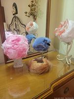 Four vintage ladies hats displayed on a wooden dresser with mirror, showing various angles and details of each hat.