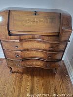 Full front view of vintage French secretary desk with closed flip-down desktop and visible marquetry decoration on wood surface and drawers.