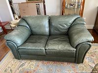 Front view of the green leather loveseat in room setting