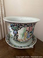 Front angle photo showing the large ceramic planter seated on the matching detached underplate, with visible painted decoration on the planter's body and floral rim pattern on both pieces.