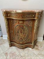 Front view showing marble top, veneer inlay and brass ormolu detail