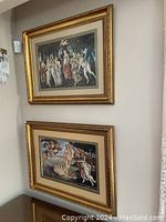 Photo of the two gold framed prints hanging vertically on a beige wall. The top print is Primavera covered with acrylic, the bottom is The Birth of Venus without cover.
