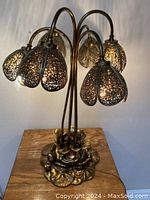 Front and side views of the pierced metal tulip lamp showing the detailed metalwork, five tulip-shaped shades, and leaf base.