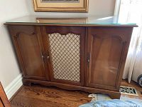Full front view of the wooden console cabinet with glass top and closed doors.