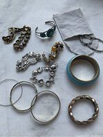 Overview of assorted bracelets showing variety of designs including silver pieces, bead cuff, chain link, hoop, and enamel bangle.
