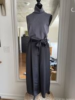 Front view of the full outfit on a mannequin - sleeveless grey mock neck top and black wide-leg pants with belt