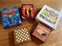 Photo showing 5 board games including Balderdash, Codenames, This That & Everything, Chess game box and wooden chessboard.