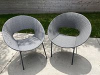 Front view of two gray woven wicker chairs on concrete patio.
