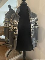 Front view of gray wool zip-up sweater with geometric patterns on mannequin