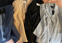 Four women's blazers laid flat together showing color and fit variety.