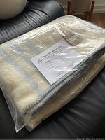 MacAusland's wool blanket folded in original plastic packaging showing size and material information on label and product tag.