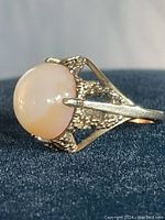 Side profile showing oval opal cabochon in textured gallery and split shoulders