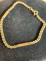 Overall view of 14kt gold chain link bracelet with rectangular bar accents on black background