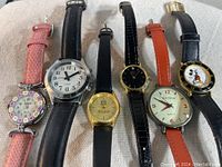 Photo showing six assorted ladies wristwatches lined up to display various dial designs and strap materials.