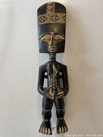Front view of carved ancestor figure showing geometric pattern on headpiece and detailed facial features