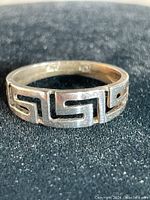 Close-up of the sterling silver ring band showing Greek key geometric pattern with black enamel filling.