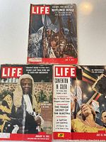 Top-down view of three LIFE magazines dated 1957 and 1960, arranged on a white surface.